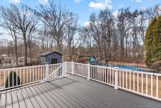 wooden terrace featuring an outbuilding and a fenced in pool