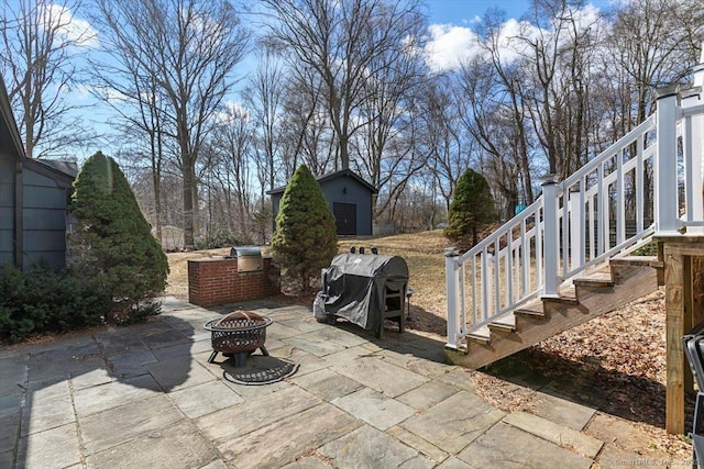 view of patio with stairs, an outdoor fire pit, an outbuilding, and a grill