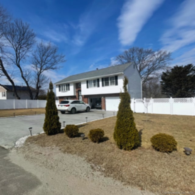 bi-level home featuring an attached garage, fence, and driveway