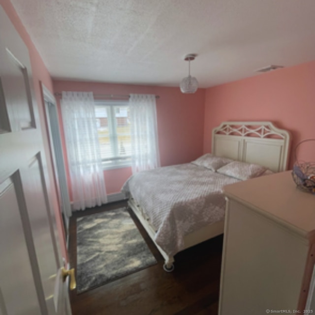 bedroom featuring a textured ceiling and wood finished floors