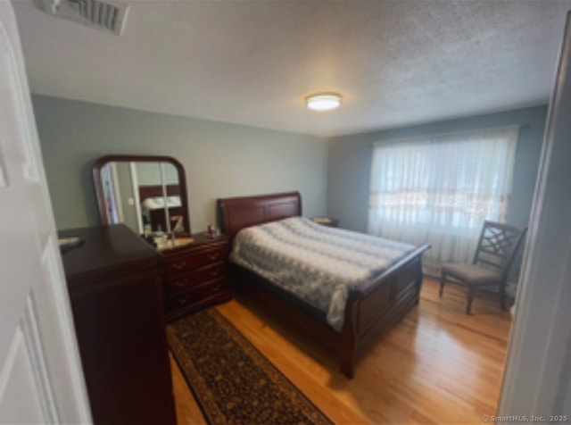 bedroom with light wood-style floors and visible vents