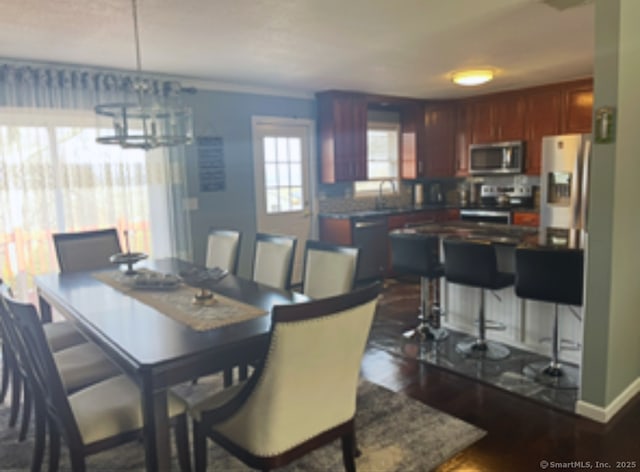 dining space with baseboards, a chandelier, and dark wood-style flooring