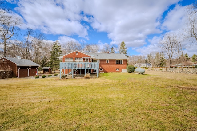 back of property featuring a garage, a deck, brick siding, an outbuilding, and a yard