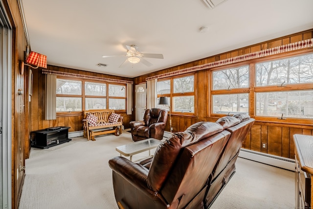 carpeted living room with a baseboard radiator, visible vents, wood walls, and a ceiling fan