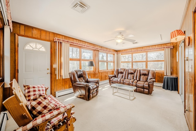 living area with a baseboard heating unit, wooden walls, carpet, and visible vents