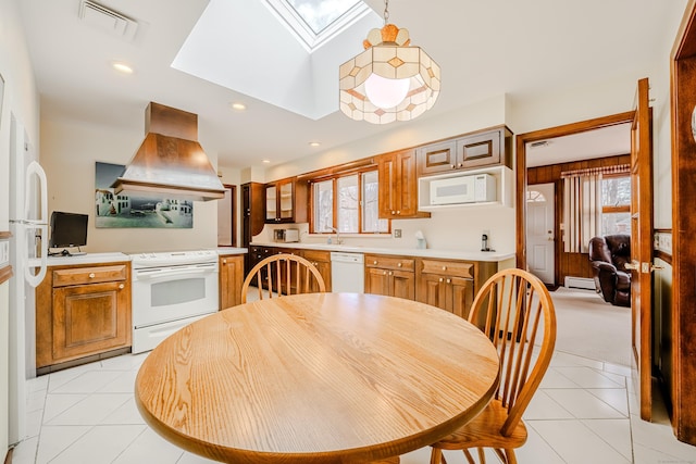 kitchen featuring a skylight, light tile patterned floors, light countertops, custom range hood, and white appliances
