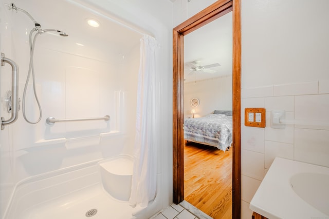 bathroom with a sink, a ceiling fan, a shower with curtain, and tile walls