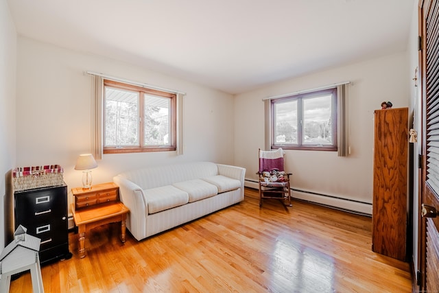 living area featuring plenty of natural light, baseboard heating, and light wood-style flooring