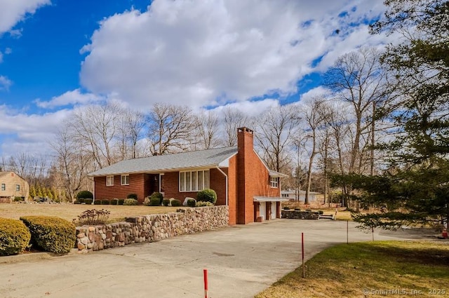view of side of home featuring an attached garage, a chimney, and concrete driveway
