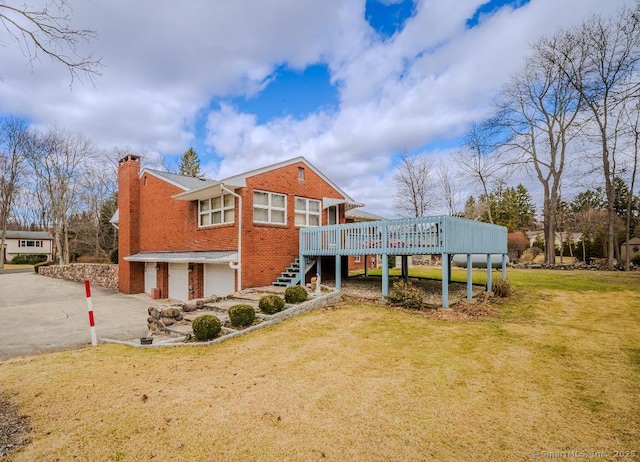 view of front of house featuring an attached garage, a chimney, stairs, a front lawn, and brick siding