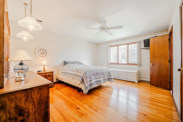 bedroom with light wood finished floors and baseboard heating