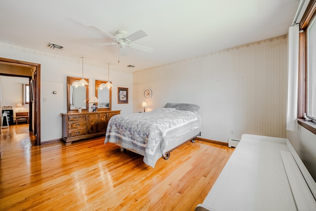 bedroom featuring visible vents, light wood-style floors, and baseboard heating