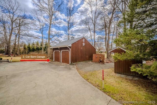 view of home's exterior featuring a detached garage, fence, an outdoor structure, and aphalt driveway