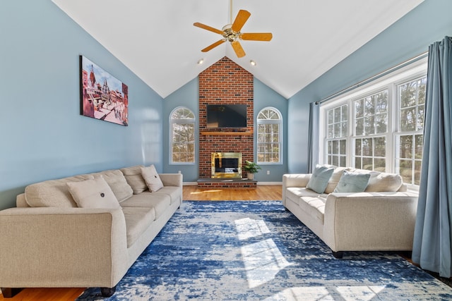 living area featuring wood finished floors, a fireplace, baseboards, ceiling fan, and vaulted ceiling