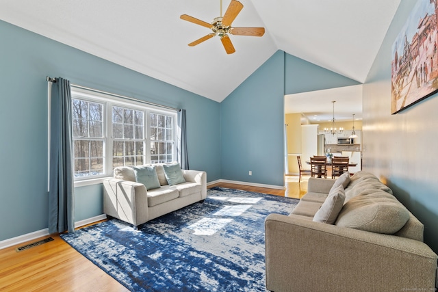 living room featuring vaulted ceiling, visible vents, baseboards, and wood finished floors