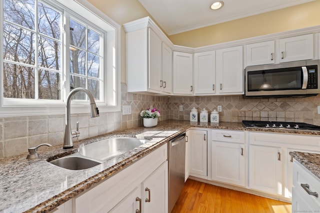 kitchen featuring light wood-style flooring, a sink, white cabinetry, stainless steel appliances, and decorative backsplash