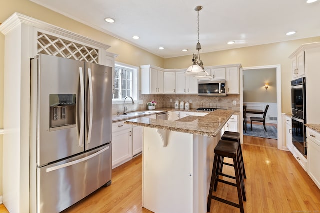 kitchen with tasteful backsplash, light wood-style flooring, stainless steel appliances, and a sink