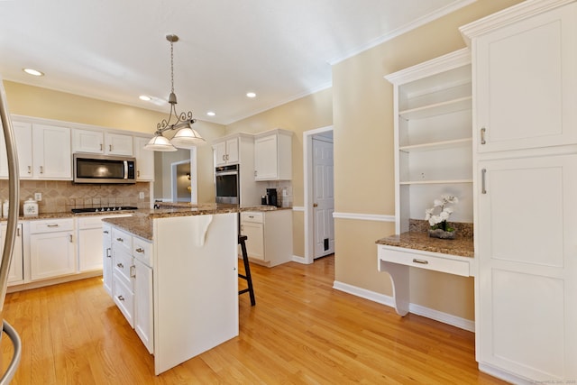 kitchen featuring a breakfast bar area, white cabinets, stainless steel appliances, and light wood-style floors