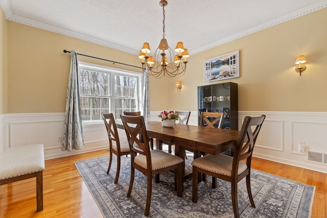 dining room with visible vents, a textured ceiling, a chandelier, and light wood finished floors