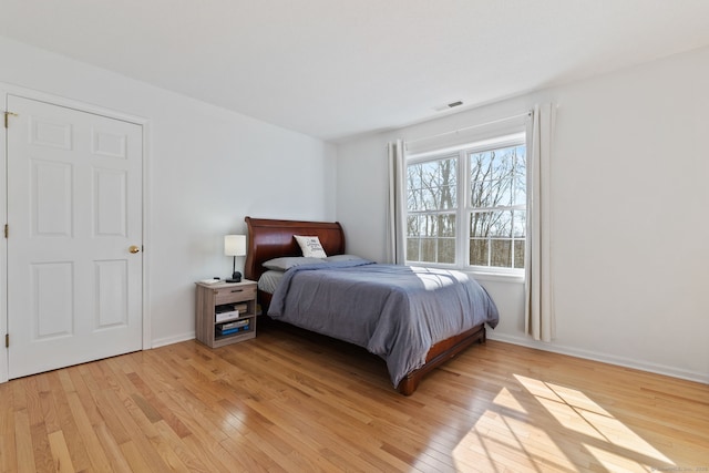 bedroom featuring light wood-style floors, visible vents, and baseboards