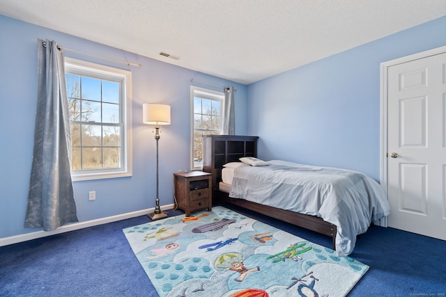 bedroom with visible vents, carpet floors, a textured ceiling, and baseboards