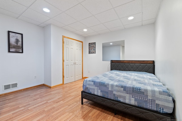 bedroom featuring visible vents, light wood-style flooring, a drop ceiling, recessed lighting, and baseboards