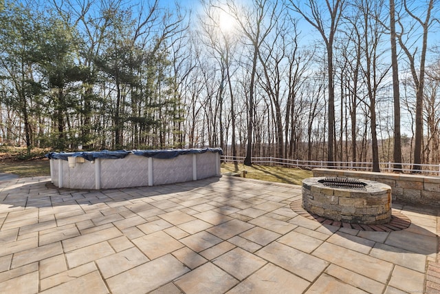 view of patio with a covered pool, fence, and an outdoor fire pit