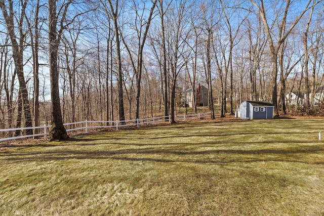 view of yard featuring an outbuilding, a storage shed, and fence