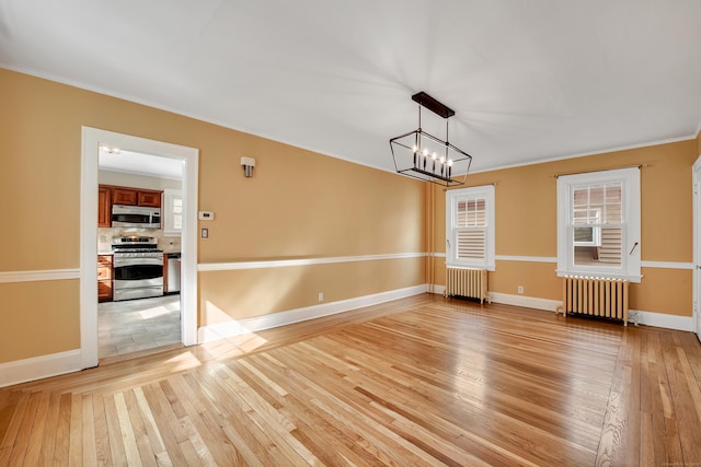 unfurnished dining area featuring baseboards, light wood-style floors, and radiator heating unit