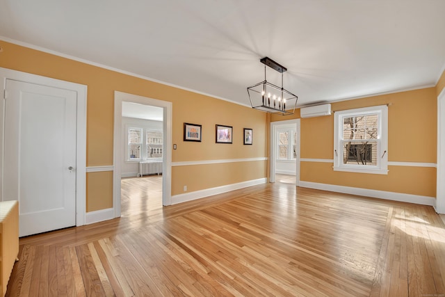 unfurnished dining area with a wall unit AC, light wood-style floors, radiator, crown molding, and baseboards