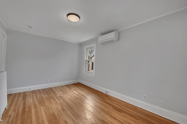 spare room with a wall unit AC, light wood-style flooring, baseboards, and ornamental molding