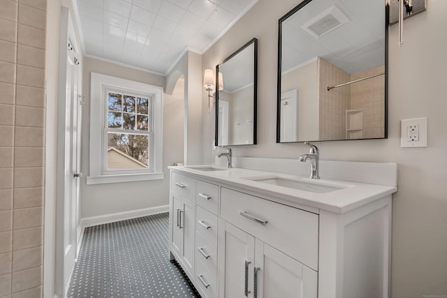 bathroom featuring a sink, visible vents, baseboards, and crown molding