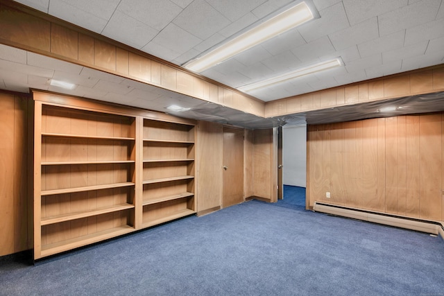 finished below grade area with a baseboard radiator, wooden walls, and carpet