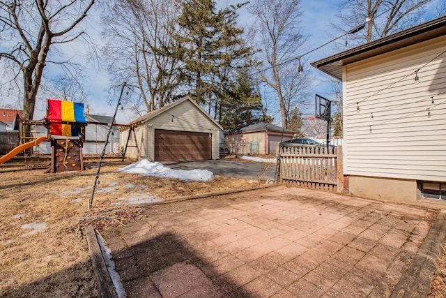 view of yard featuring a garage, fence, an outdoor structure, and a playground