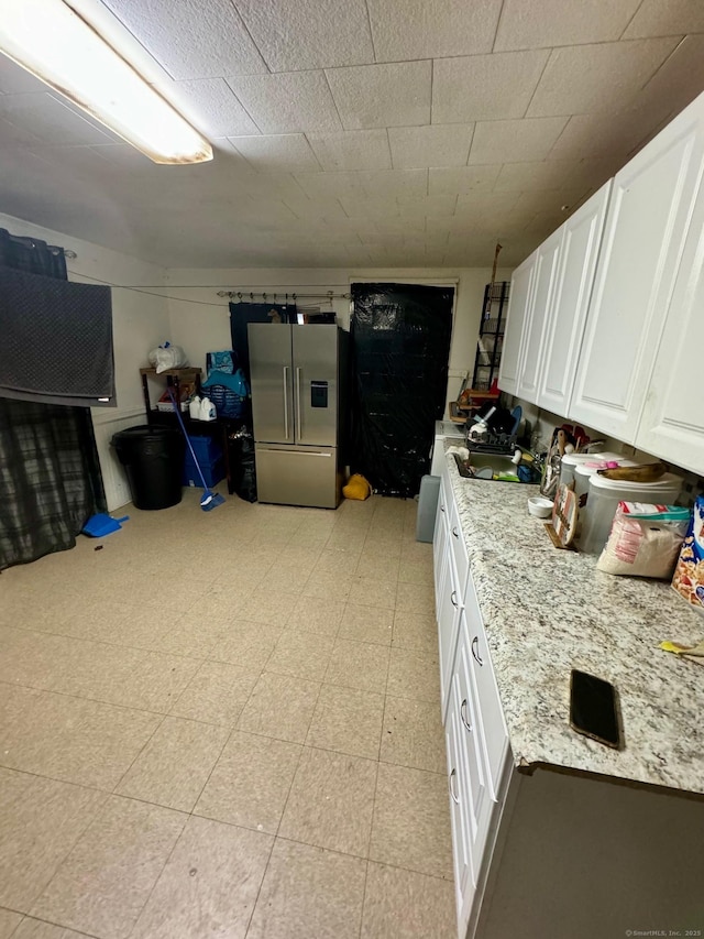 kitchen featuring white cabinets, light floors, stainless steel refrigerator with ice dispenser, and light stone countertops