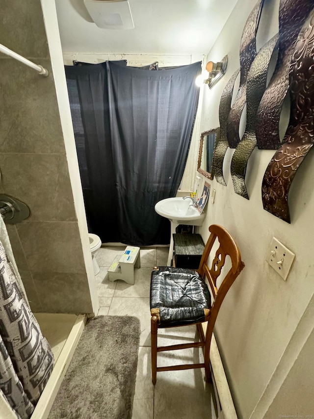 bathroom with a sink, toilet, a shower stall, and tile patterned floors