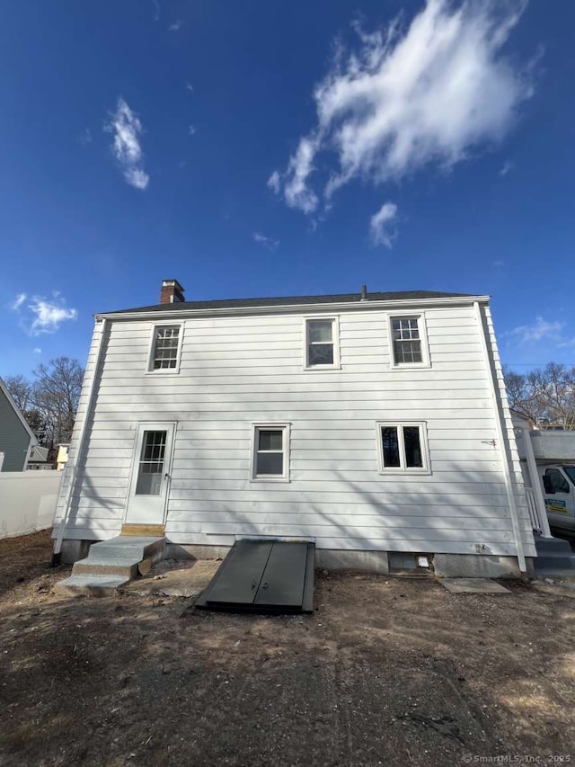 back of property featuring entry steps and a chimney