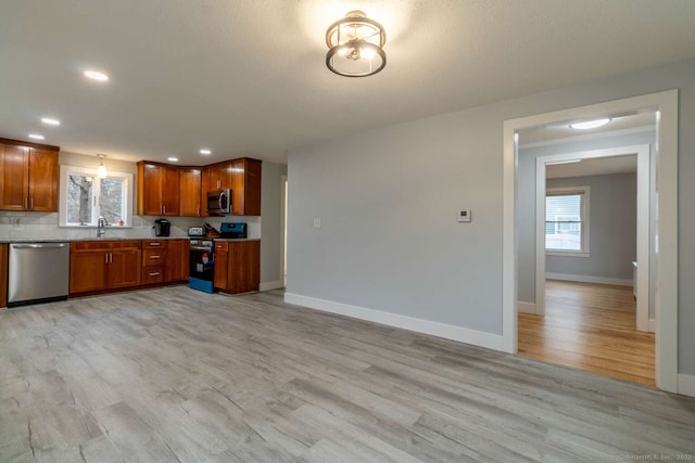 kitchen featuring a sink, light wood-style flooring, baseboards, appliances with stainless steel finishes, and recessed lighting