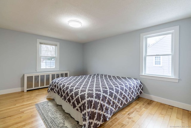 bedroom featuring baseboards, hardwood / wood-style floors, and a textured ceiling