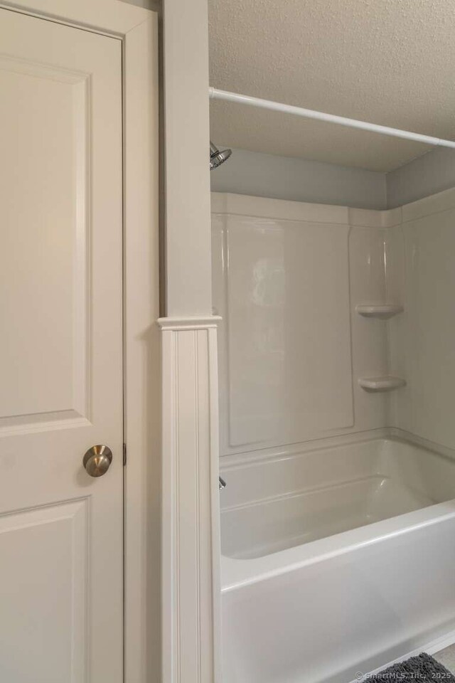 bathroom with a bath, a textured ceiling, and a shower