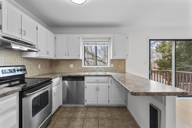 kitchen featuring a peninsula, a sink, under cabinet range hood, appliances with stainless steel finishes, and backsplash