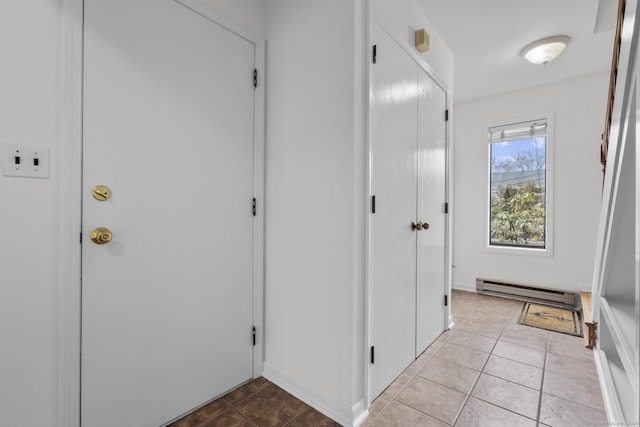 hall featuring a baseboard heating unit and light tile patterned flooring