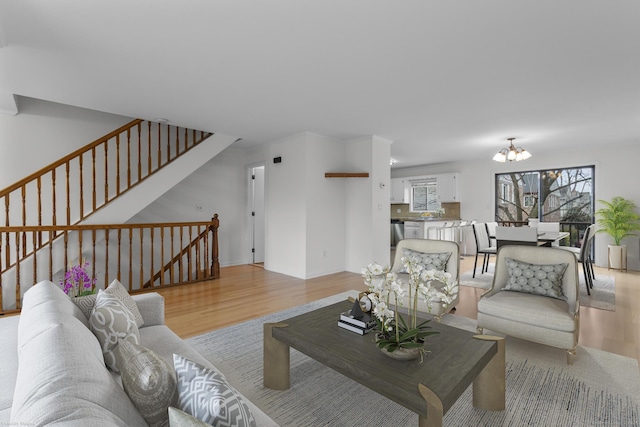 living room featuring a chandelier, stairway, and light wood finished floors