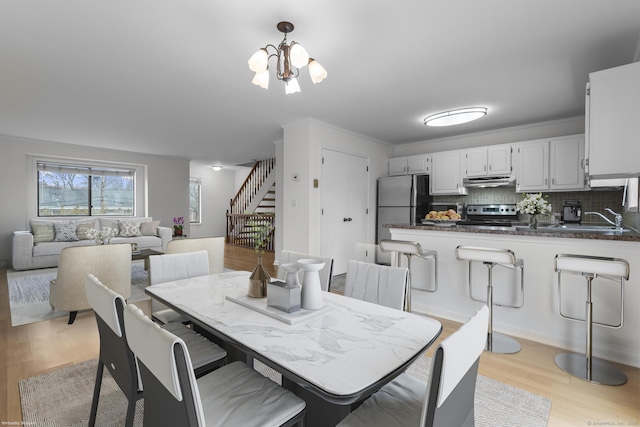 dining area featuring stairway, an inviting chandelier, and light wood-style floors