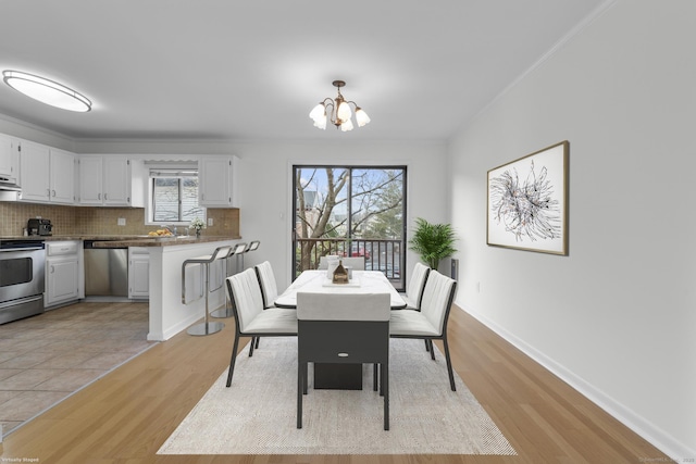 dining space with an inviting chandelier, light wood-style flooring, and baseboards