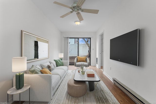 living area featuring a baseboard heating unit, wood finished floors, baseboards, and ceiling fan