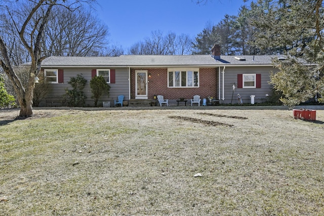 ranch-style home with a front yard, brick siding, and a chimney