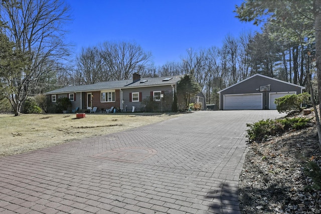 ranch-style home featuring an outbuilding, a chimney, and a garage