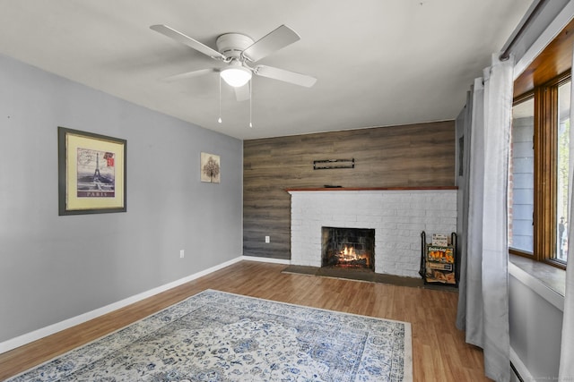 living area featuring baseboards, wood finished floors, and a fireplace