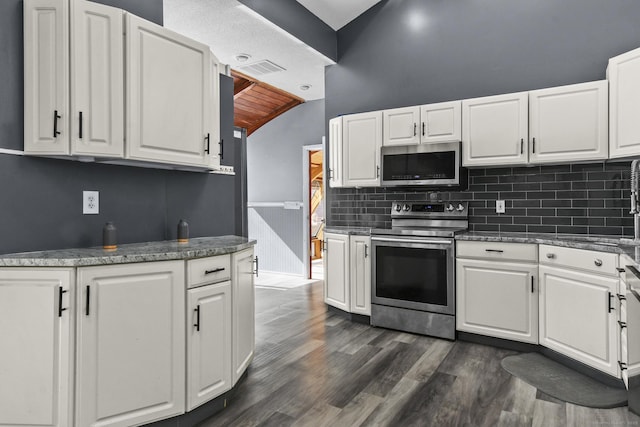 kitchen featuring lofted ceiling, decorative backsplash, stainless steel appliances, white cabinetry, and dark wood-style flooring